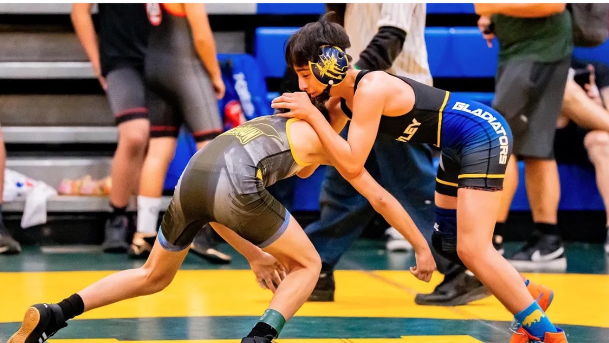 A Brawley Gladiators wrestler in blue and gold shooting a takedown at a tournament